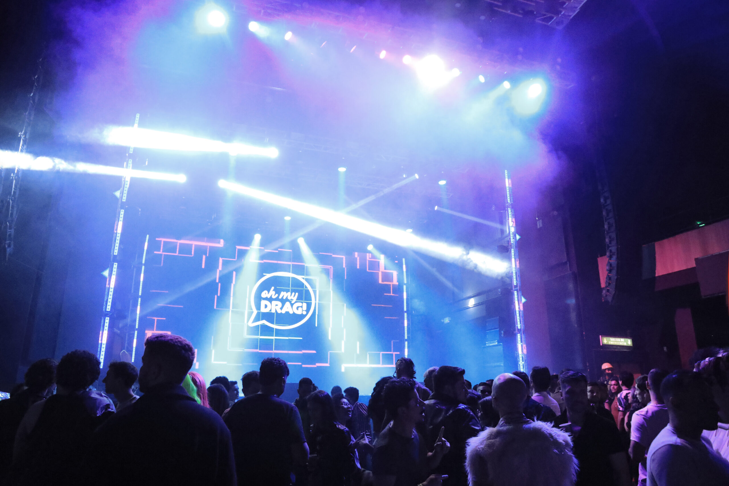 Escenario de Oh My Drag! con el logo en pantalla y el p&uacute;blico